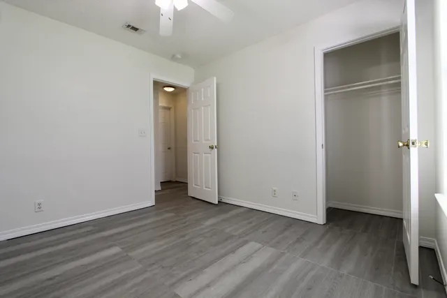 an empty room with wooden floor cabinet and windows