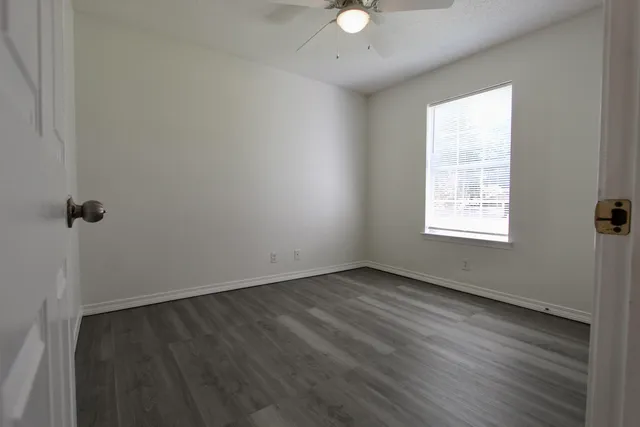 an empty room with wooden floor and windows