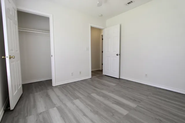 a view of an empty room with wooden floor and closet