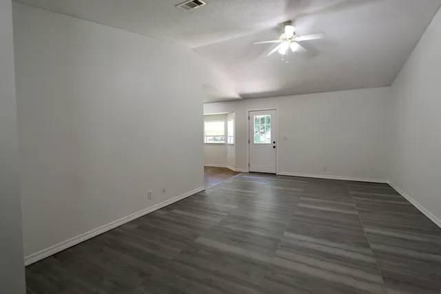 an empty room with wooden floor and window