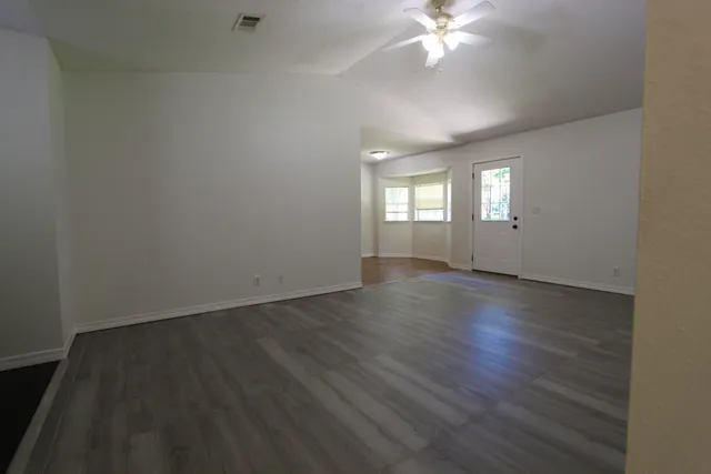 an empty room with wooden floor and windows
