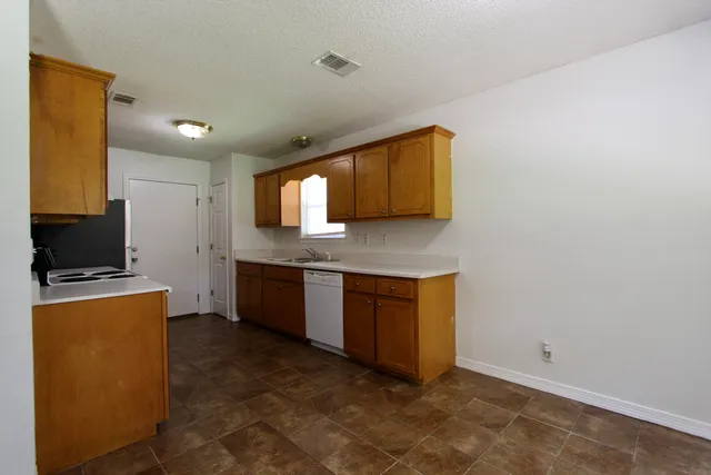 a kitchen with granite countertop a sink a stove top oven a counter space and cabinets