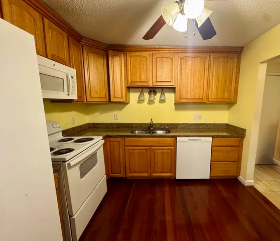 a kitchen with granite countertop wooden floors and white stainless steel appliances