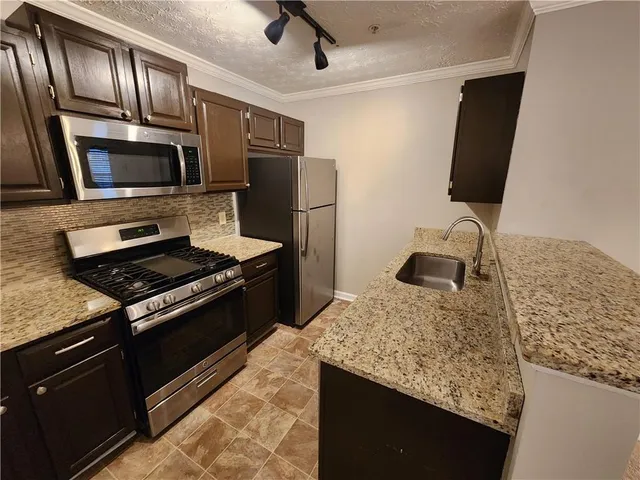 a kitchen with stainless steel appliances granite countertop a stove microwave and refrigerator