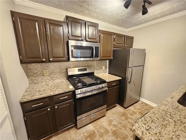 a kitchen with granite countertop wooden cabinets and stainless steel appliances