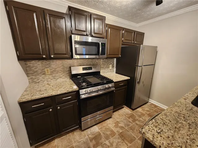 a kitchen with granite countertop wooden cabinets and stainless steel appliances