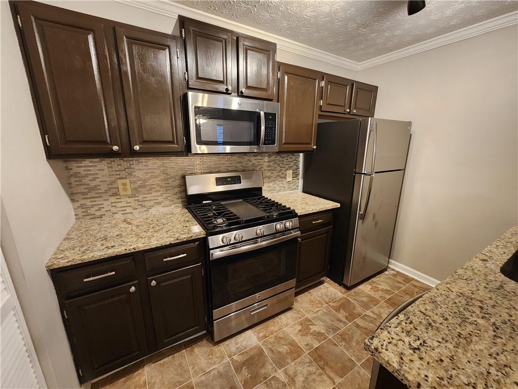 1411 Keys Crossing Drive Northeast Brookhaven, GA 30319 - Photo 3 of 24 a kitchen with granite countertop wooden cabinets and stainless steel appliances
