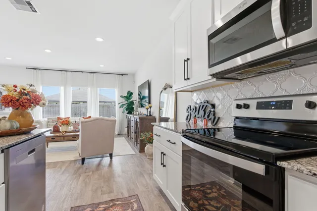 a very nice looking dining room with kitchen island white furniture a sink a rug and a potted plant