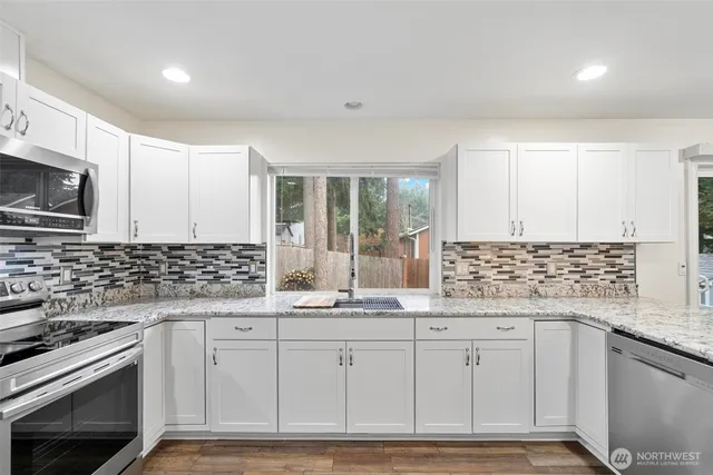 a kitchen with granite countertop a sink stainless steel appliances and cabinets