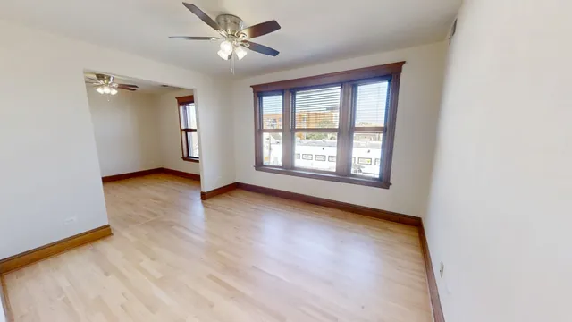 a view of an empty room with a window and wooden floor