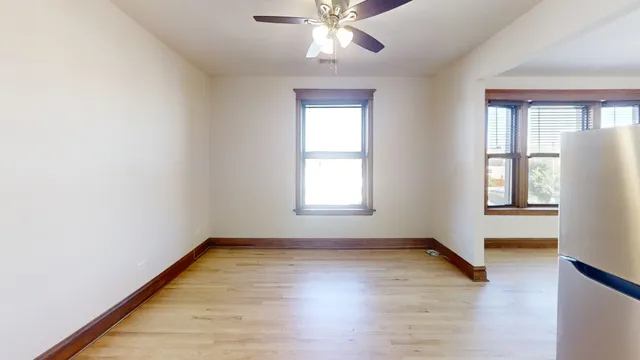 an empty room with wooden floor chandelier fan and windows