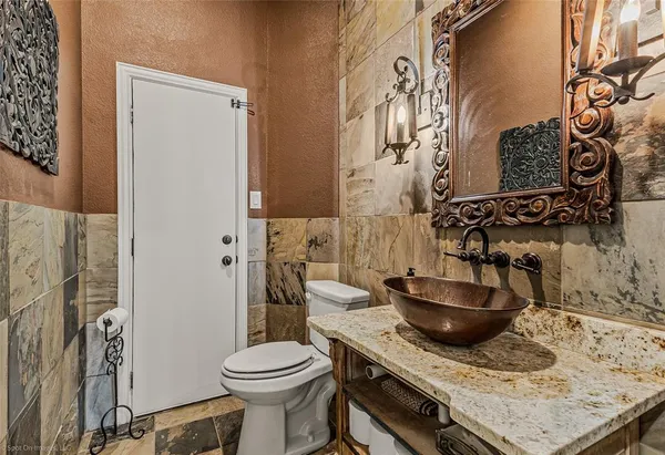 a bathroom with a granite countertop sink a toilet and a blue shower