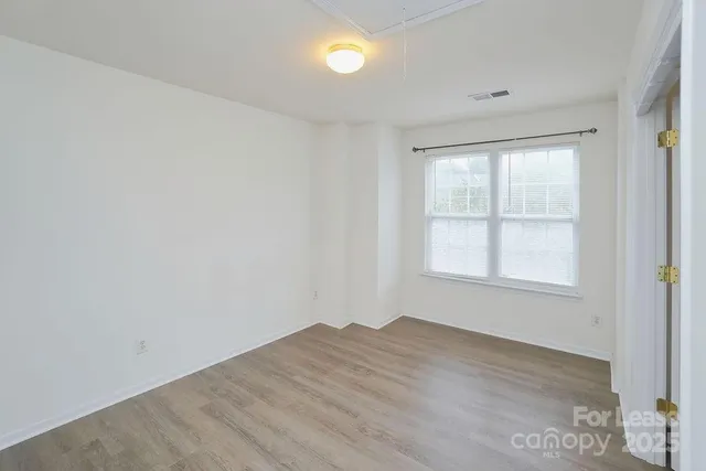 an empty room with a window and wooden floor