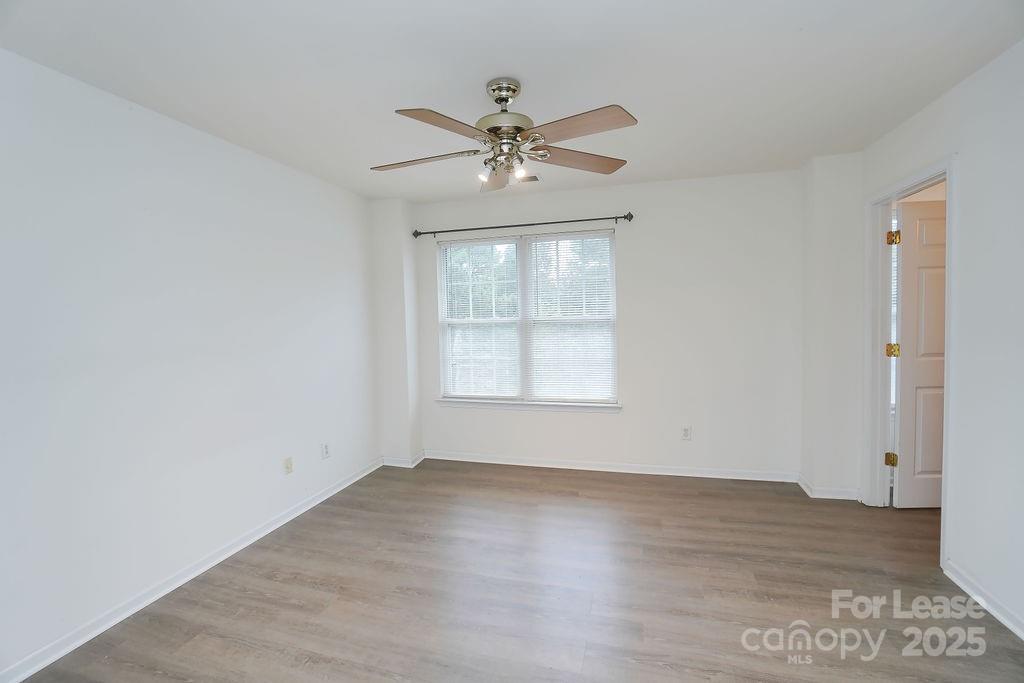 9858 Treeside Lane Matthews, NC 28105 - Photo 20 of 22 an empty room with wooden floor chandelier fan and windows
