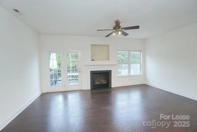 an empty room with windows fireplace and wooden floor