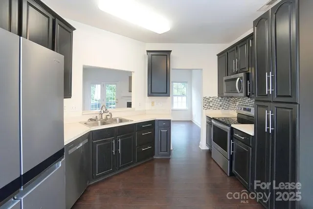 a kitchen with stainless steel appliances granite countertop a refrigerator a stove a sink and a microwave