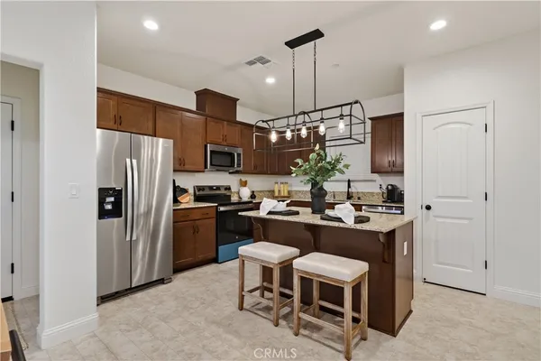 a kitchen with a refrigerator a stove a sink and chairs