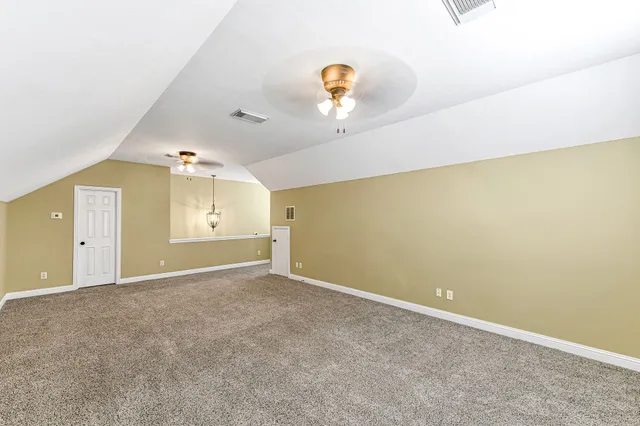 an empty room with a chandelier fan and wooden floor