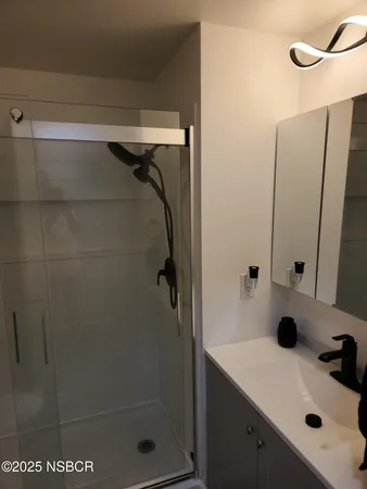 a bathroom with a sink vanity and shower