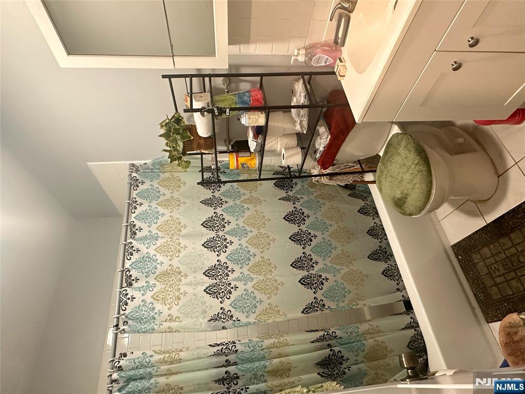 154 Butler Street Paterson, NJ 07524 - Photo 26 of 26 a bathroom with a sink a toilet and shower curtain