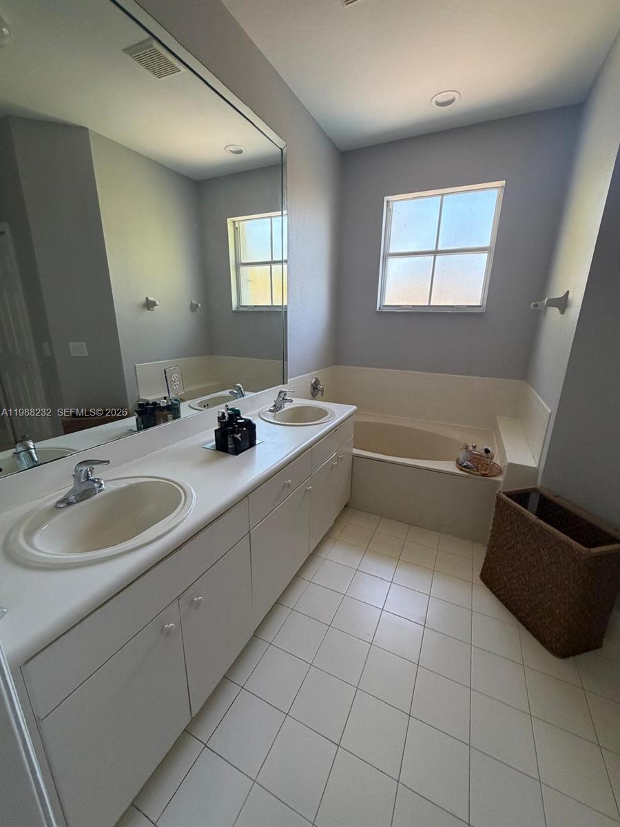 10837 Southwest 242nd Street Homestead, FL 33032 - Photo 14 of 19 a bathroom with a double vanity sink a mirror and a bathtub
