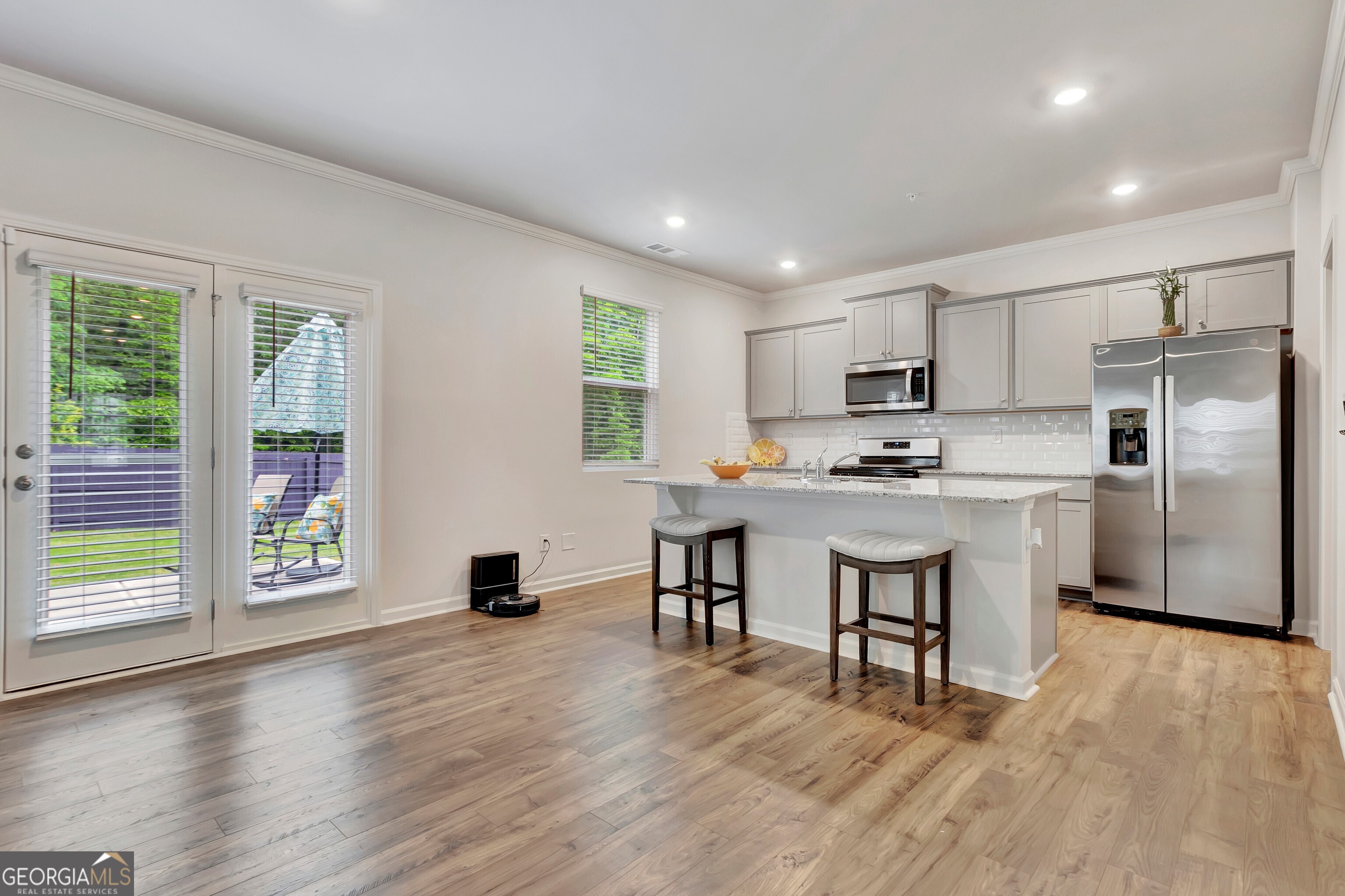 7730 Demeter Drive Fairburn, GA 30213 - Photo 14 of 47 a kitchen with a refrigerator a stove a microwave oven a sink and a dining table with wooden floor