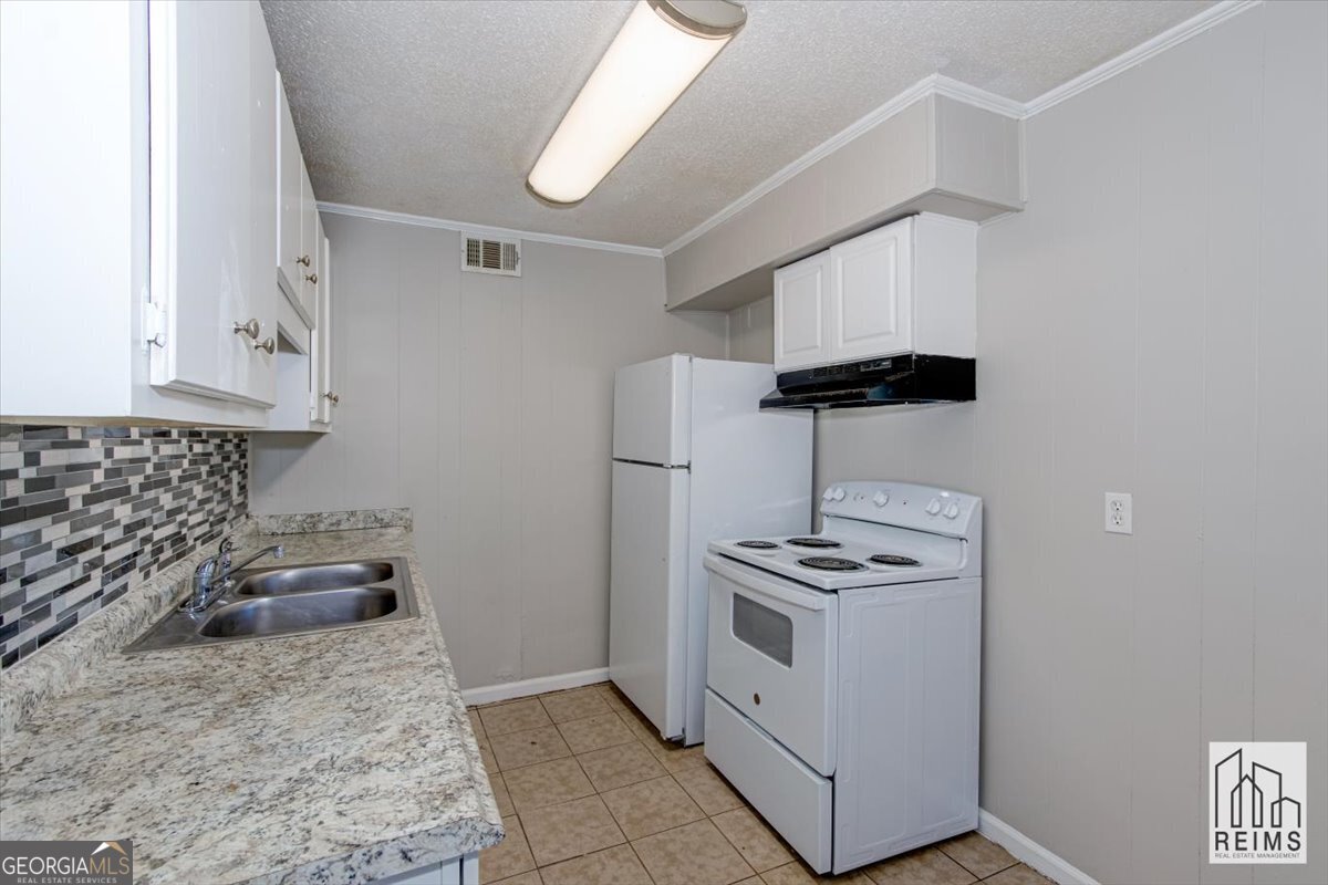 1232 12th Street, Unit F Augusta, GA 30901 - Photo 18 of 27 a kitchen with stainless steel appliances granite countertop a sink stove a refrigerator and cabinets
