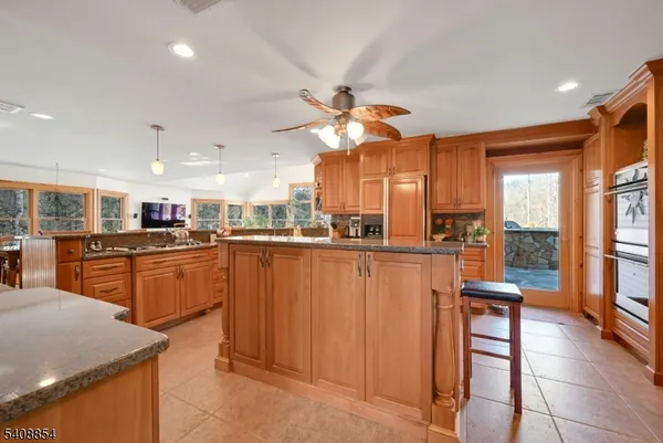 a kitchen with stainless steel appliances granite countertop a refrigerator a sink dishwasher and a stove with wooden floor