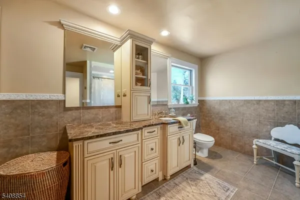 a spacious bathroom with a granite countertop toilet a sink and a mirror