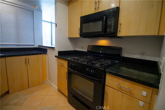 a kitchen with stainless steel appliances granite countertop a refrigerator a stove and a sink with wooden floor