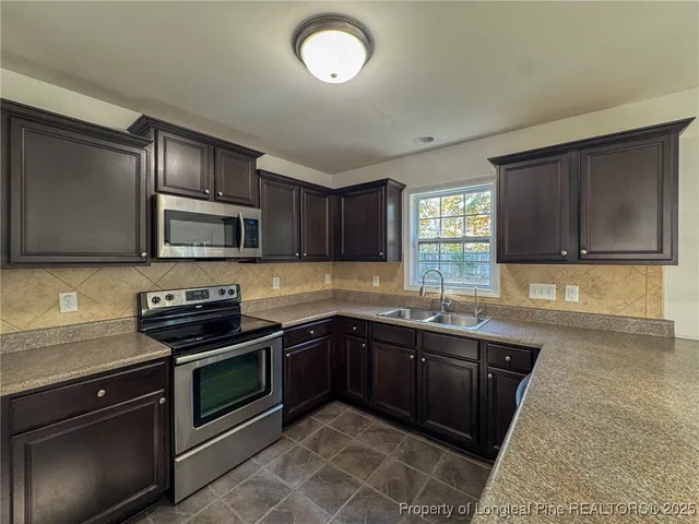 a kitchen with stainless steel appliances granite countertop a sink stove and microwave