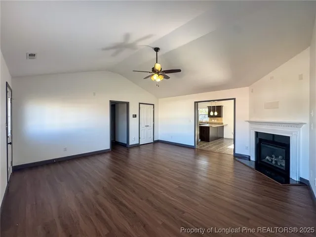 an empty room with wooden floor fireplace and windows
