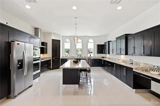 a large kitchen with a large counter top a sink stainless steel appliances and cabinets