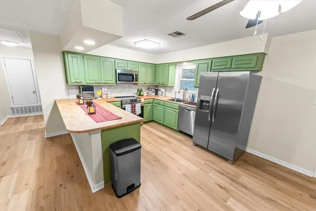 a kitchen with kitchen island a island wooden floor stainless steel appliances and cabinets