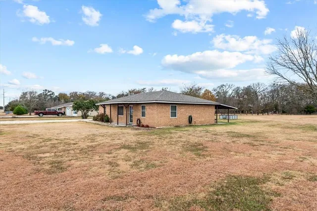 a view of a house with a yard and large tree