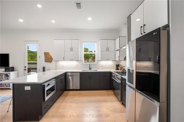a kitchen with kitchen island a sink appliances and a living room view