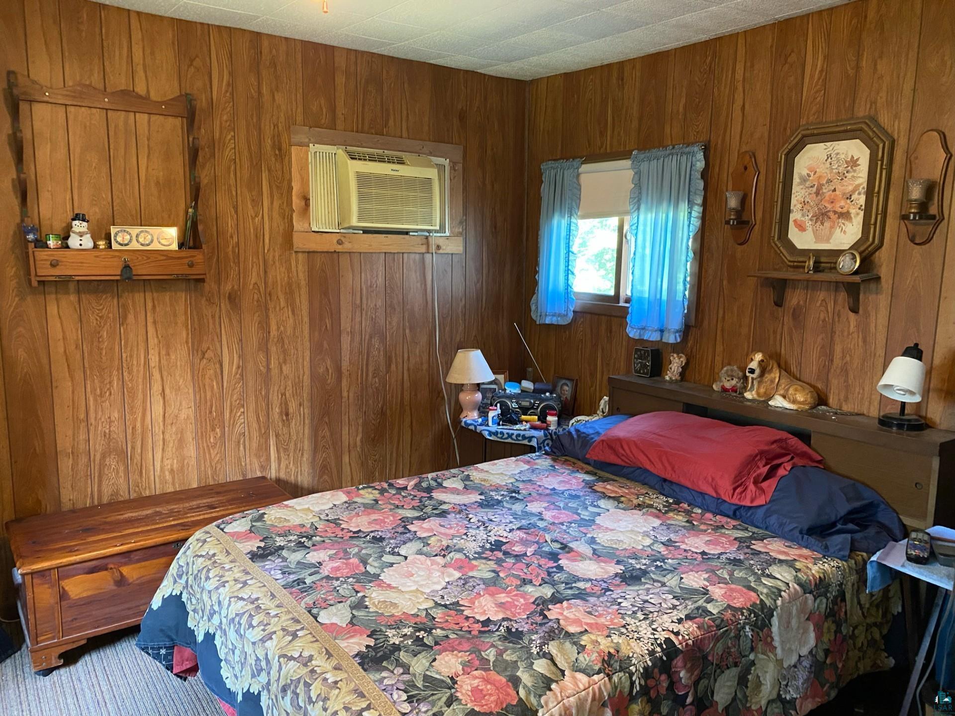 W6402 Old Bass Lake Road Minong, WI 54859 - Photo 10 of 18 Bedroom featuring wood walls and an AC wall unit