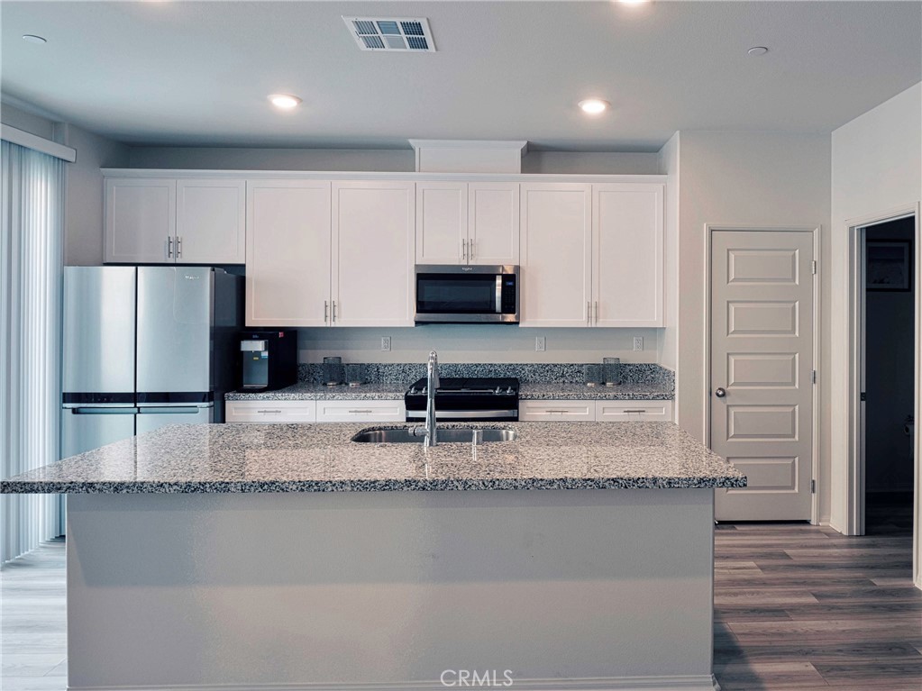 40336 Birchfield Drive Temecula, CA 92591 - Photo 13 of 39 a kitchen with granite countertop a refrigerator a stove and a sink with wooden floor