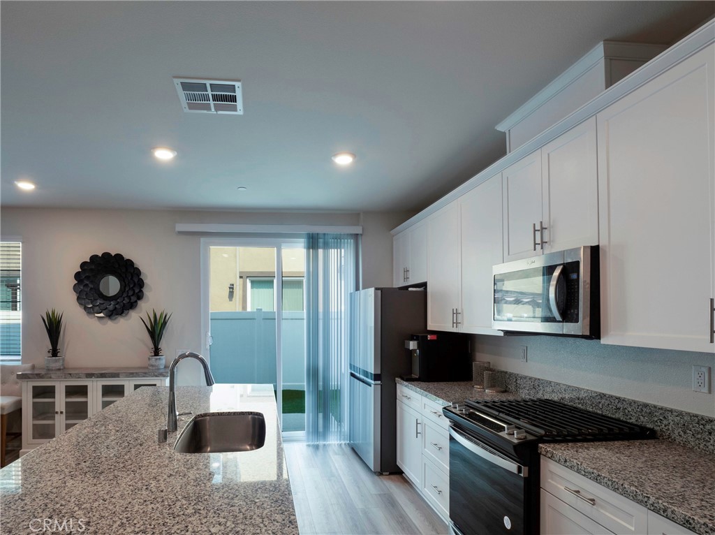 40336 Birchfield Drive Temecula, CA 92591 - Photo 15 of 39 a kitchen with granite countertop a stove a sink and a refrigerator
