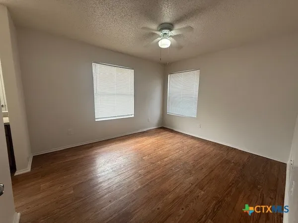 an empty room with wooden floor and windows