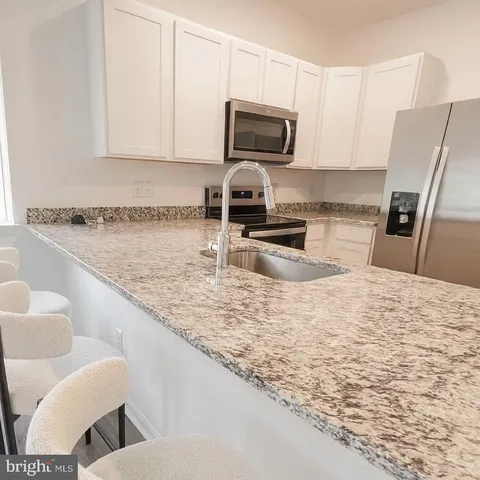 a kitchen with granite countertop a sink a stove top oven a chimney and cabinets