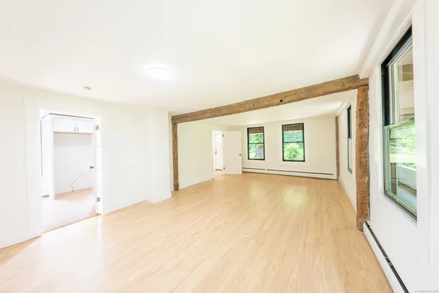 a view of an empty room with wooden floor and a window