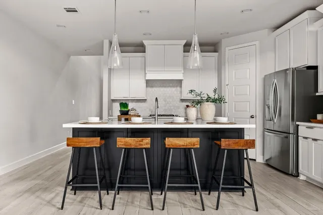 a kitchen with stainless steel appliances a table chairs refrigerator and sink