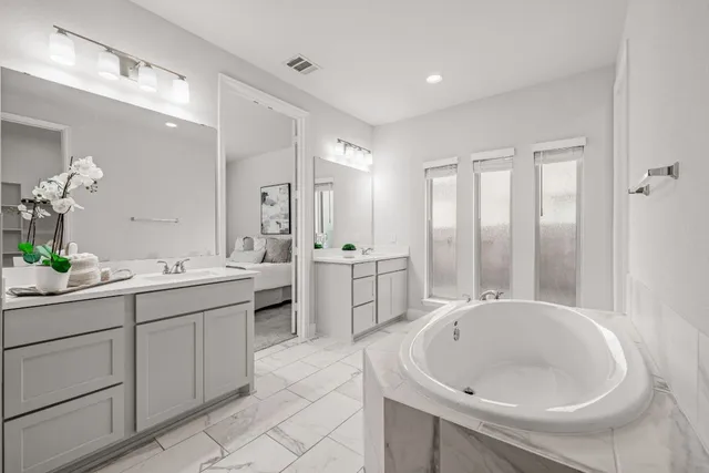 a large white bathroom with a double vanity sink a mirror and a bathtub
