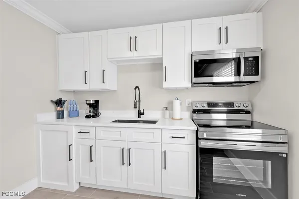 a kitchen with white cabinets and sink