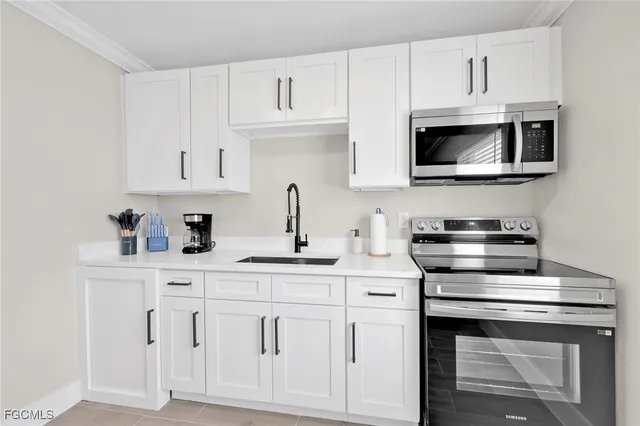 a kitchen with white cabinets and sink