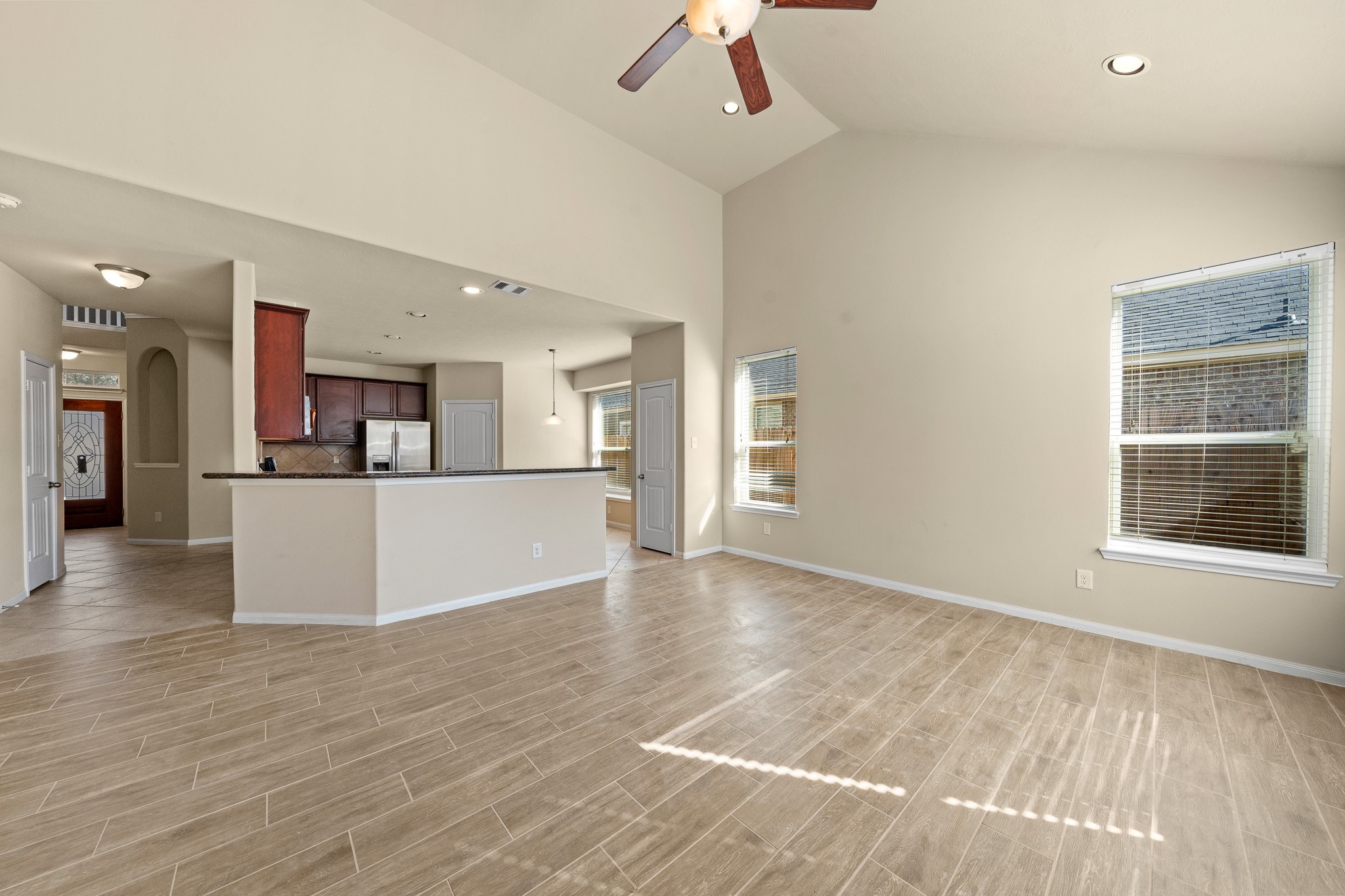 24735 Colonial Maple Drive Katy, TX 77493 - Photo 12 of 32 a view of a kitchen with a refrigerator a kitchen island wooden floor and a living room view
