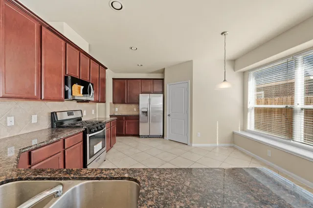 a kitchen with stainless steel appliances granite countertop a sink refrigerator stove and microwave