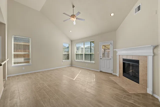 a view of an empty room with chandelier fan and fire place