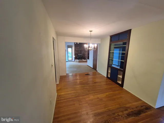 a view of a hallway with wooden floor and a bathroom